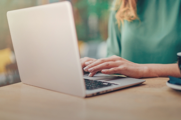 Με τα χέρια της στο touch pad του laptop της, μια γυναίκα με οπτική αναπηρία πλοηγείται για να ενημερωθεί για τις επιλογές στην εξυπηρέτησή της στην τράπεζα. Εικονίδιο για οπτική αναπηρία.
